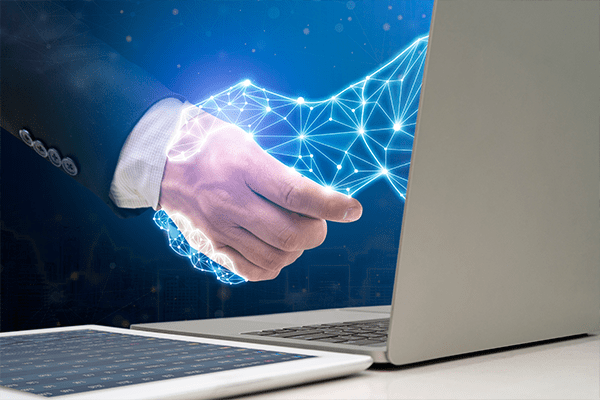 Person in a suit shaking hands with a glowing digital hand emerging from a laptop